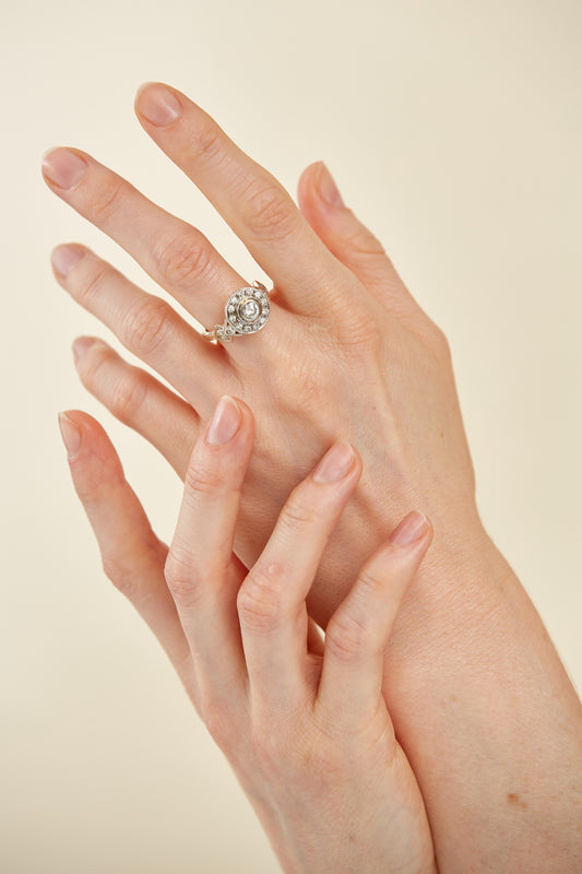 Art Deco–inspired 18K gold ring with a bezel-set centre diamond and surrounding halo. A bold, symmetrical masterpiece with vintage glamour.