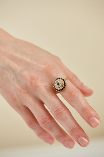 Ornate 18K gold ring with central garnet and raised filigree dome. A vintage-inspired design with bold dimension and deep red brilliance.
